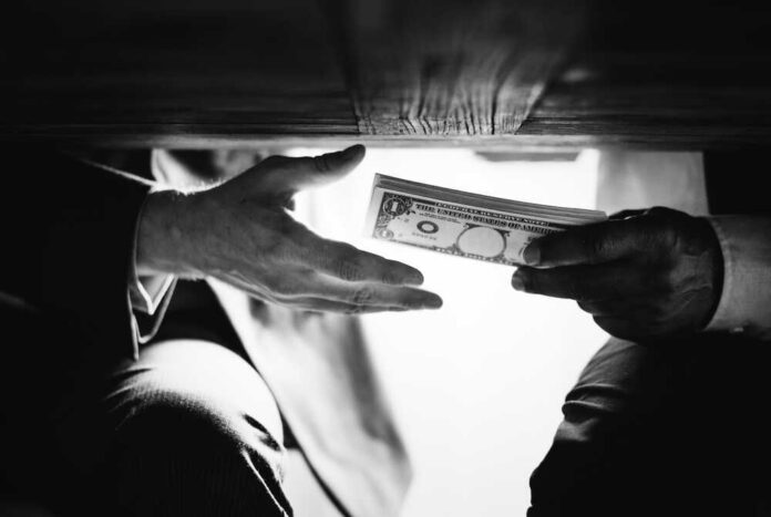 Hands,Passing,Money,Under,The,Table,Corruption,And,Bribery