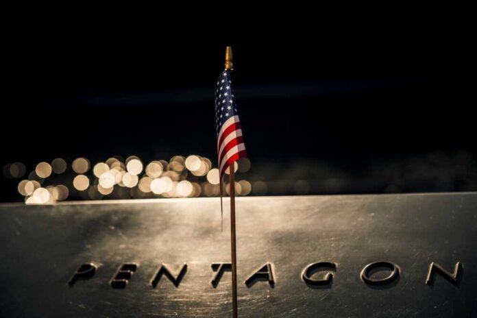 shutterstock_2321355077.jpg featured image American flag above engraved Pentagon sign at night