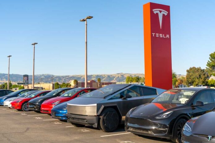 shutterstock_2461159891.jpg featured image Tesla cars parked outside dealership with sign nearby