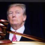Gavel in foreground with blurry man in background.