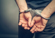 Person with handcuffs behind their back.