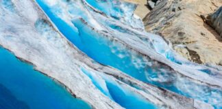 Blue glacier ice with crevasses and rocky surface