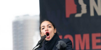 Alexandria Ocasio-Cortez passionately speaking at a podium outside.
