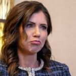 Kristi Noem with long dark hair frowns slightly.