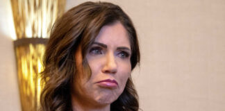 Kristi Noem with long dark hair frowns slightly.