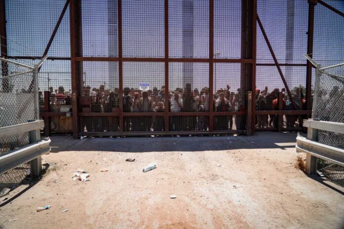 shutterstock_2298883197.jpg featured image People standing behind a fence on a dusty path.