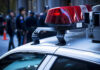 Police car lights with officers blurred in background.