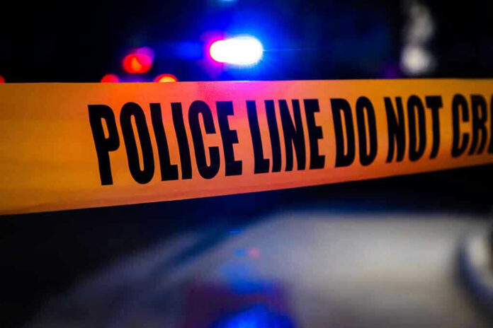 2408118125 Police tape with flashing lights in the background