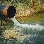 Water flowing from large rusty pipe into river