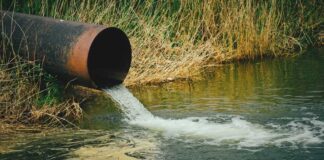 Water flowing from large rusty pipe into river