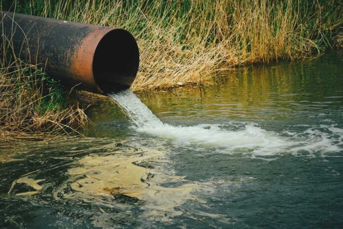 shutterstock_2161054429.jpg featured image Water flowing from large rusty pipe into river
