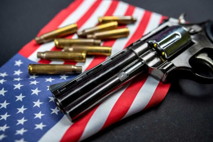 shutterstock_2206507241.jpg Revolver and bullets on American flag background