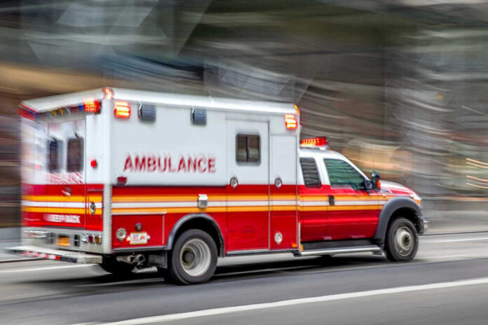 shutterstock_1495131698.jpg Red and white ambulance driving on a city street