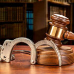 Wooden gavel and handcuffs on a table