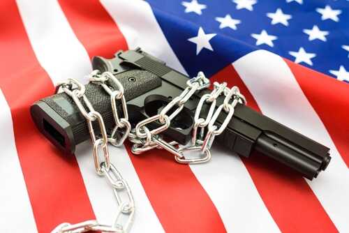 A handgun wrapped in chains on an American flag