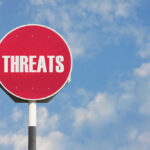 Red sign with the word threats against sky