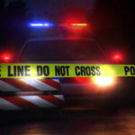 Police car with flashing lights behind caution tape