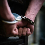 Close-up of hands in handcuffs behind back