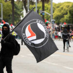 Person holding antifascist action flag at a protest