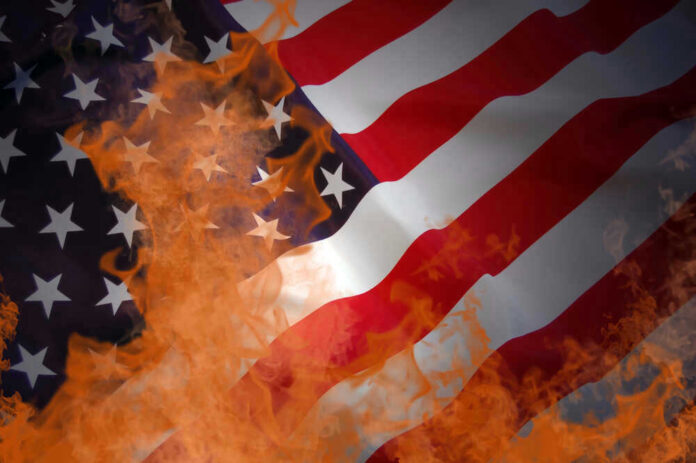 American flag partially set on fire with orange flames
