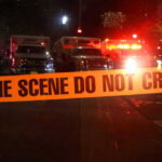 Crime scene tape with emergency vehicles in background