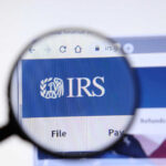 NOW: IRS Workforce SLASHED Magnifying glass focusing on IRS website logo