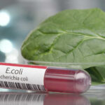 E. Coli Meat Shock — Millions at Hidden Risk Test tube labeled E. coli next to a spinach leaf in a petri dish