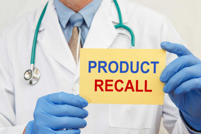 Doctor holding a product recall sign in gloves