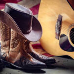 Country Star Confesses — Career Was Hanging By Thread Cowboy boots and hat with guitar and flag.