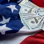 MONEY ALERT: 111% Boom Ignites Market Stack of hundred dollar bills on an American flag