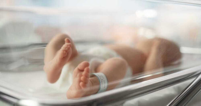 Newborn baby in hospital bassinet with ID band.