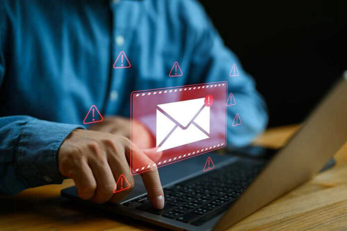 Person typing on laptop with mail warning icons.