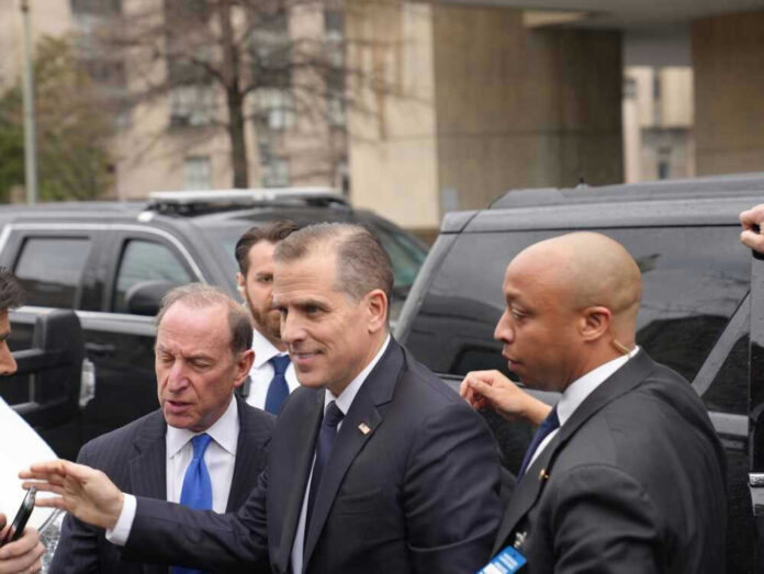 Hunter Biden standing by black SUVs outdoors.