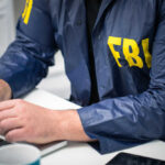 FBI SPYING Storm Hits Top GOP Senators Person in FBI jacket working on laptop.