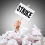 Holiday NIGHTMARE — Worker Strike Coming Hand holding strike sign amid crumpled paper pile