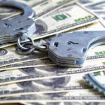 $102 Million HEIST — Four MORE Arrested Handcuffs on a pile of one hundred dollar bills.