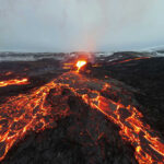 Lava flowing from volcanic eruption under gray sky