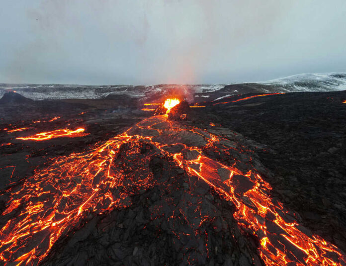 Lava flowing from volcanic eruption under gray sky