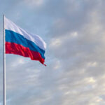 Russia LASERS Pilots – WAR Warning! Russian flag waving against a cloudy sky.