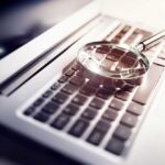 A magnifying glass resting on a laptop keyboard