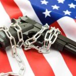A handgun wrapped in chains on an American flag