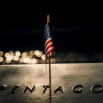 American flag above engraved Pentagon sign at night