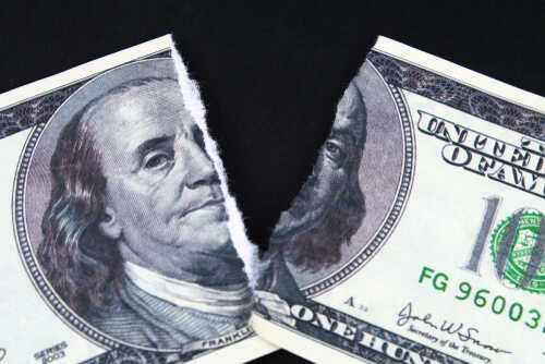 A torn hundred dollar bill featuring Benjamin Franklin