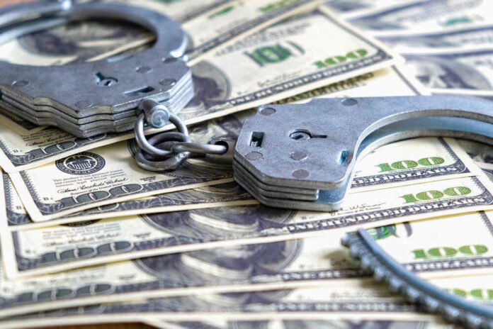 Handcuffs on a pile of one hundred dollar bills.