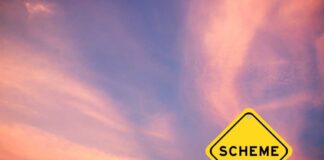 A yellow warning sign with the word 'SCHEME' against a colorful sky