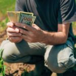 A farmer counting cash in a field