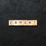 Barry Manilow’s Lung Cancer Shock Wooden letters spelling the word 'Cancer' on a black textured background