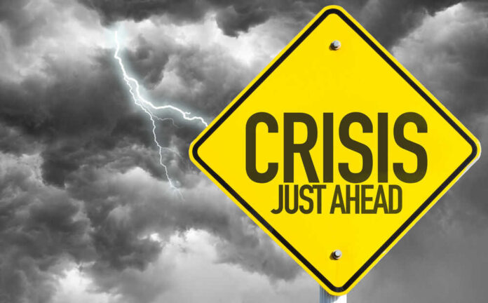 Yellow sign reading Crisis Just Ahead with stormy sky
