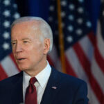 Joe Biden speaking, American flags in the background.