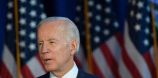 Joe Biden speaking, American flags in the background.